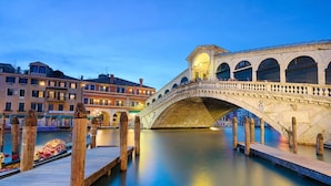 A stone bridge over a canal with wooden walkways, surrounded by buildings with arched windows. - San Marco Design Suites (Venice)