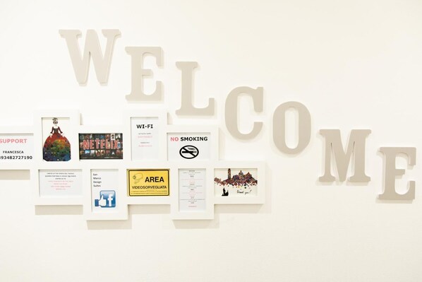 A wall with large letters spelling "WELCOME" and various framed items including a dress, a movie poster, and a sign.