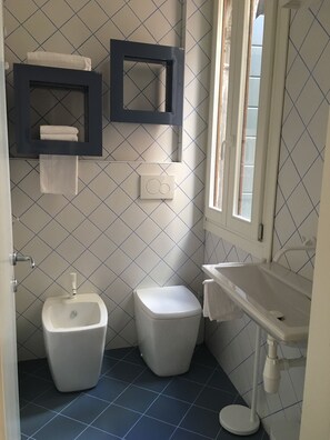 A bathroom with a toilet, bidet, and sink. There are two towel racks and a window. - San Marco Design Suites (Venice)