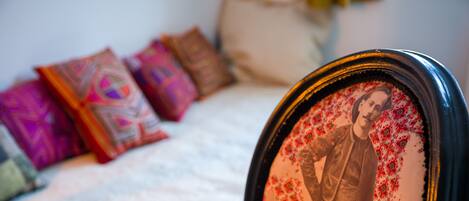A bed with a white textured cover, a decorative pillow, and a framed picture on the headboard.