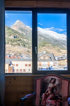 Une pièce dotée d’une grande fenêtre donnant sur une montagne et un village.