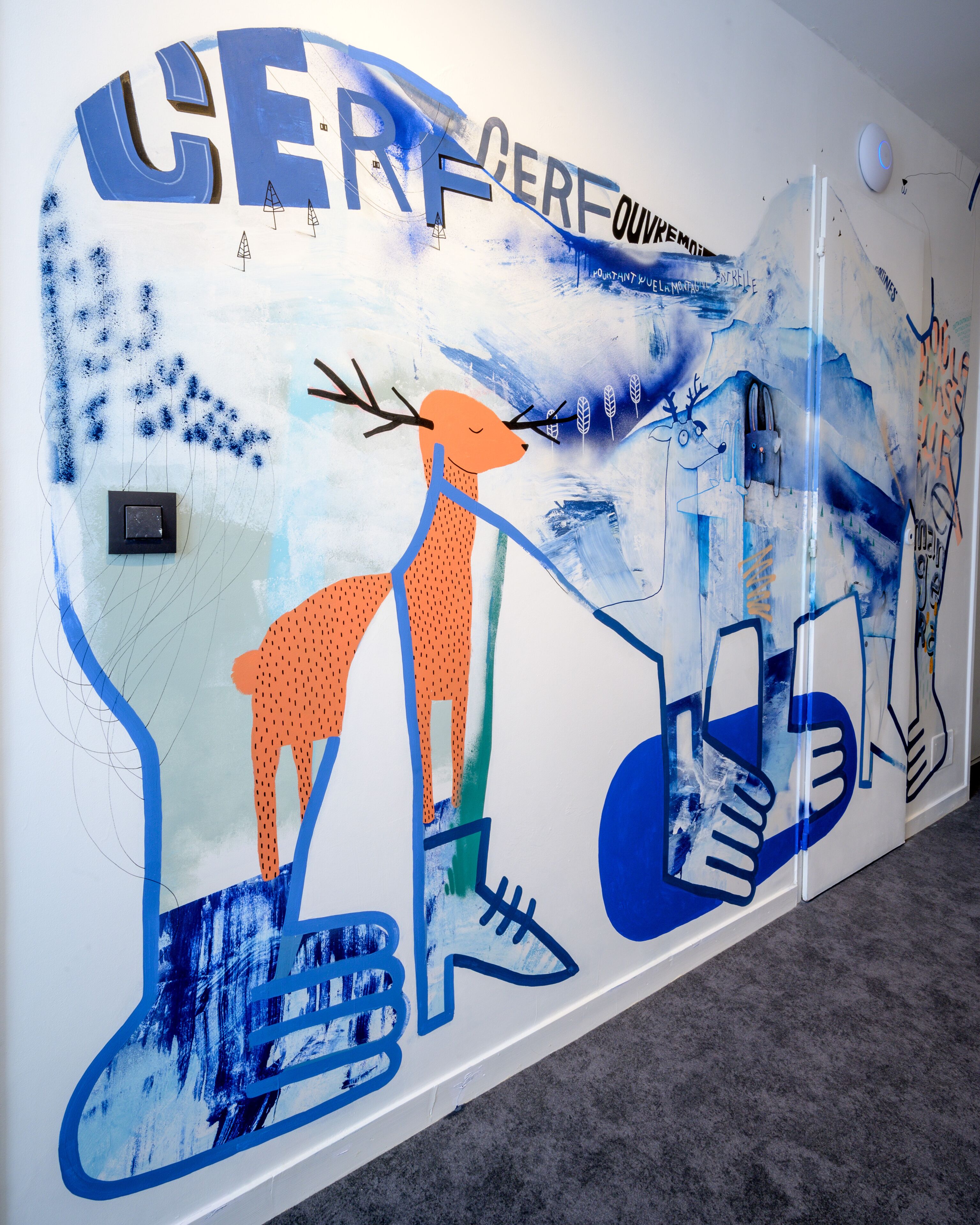 A wall with abstract art and text, including 'CERF' and 'OUVREM'.