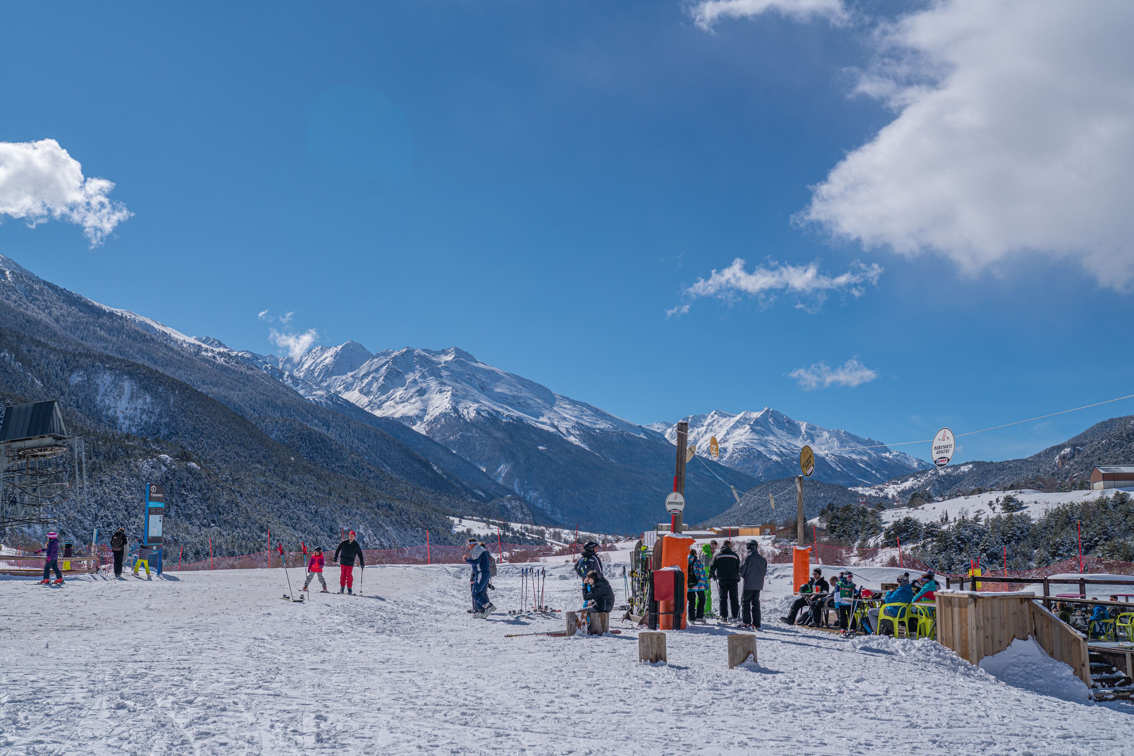 A ski resort with snow-covered mountains in the background, a ski lift, and people skiing.