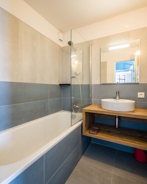 Une salle de bain moderne avec une douche à parois de verre, une baignoire blanche et un meuble-lavabo en bois.