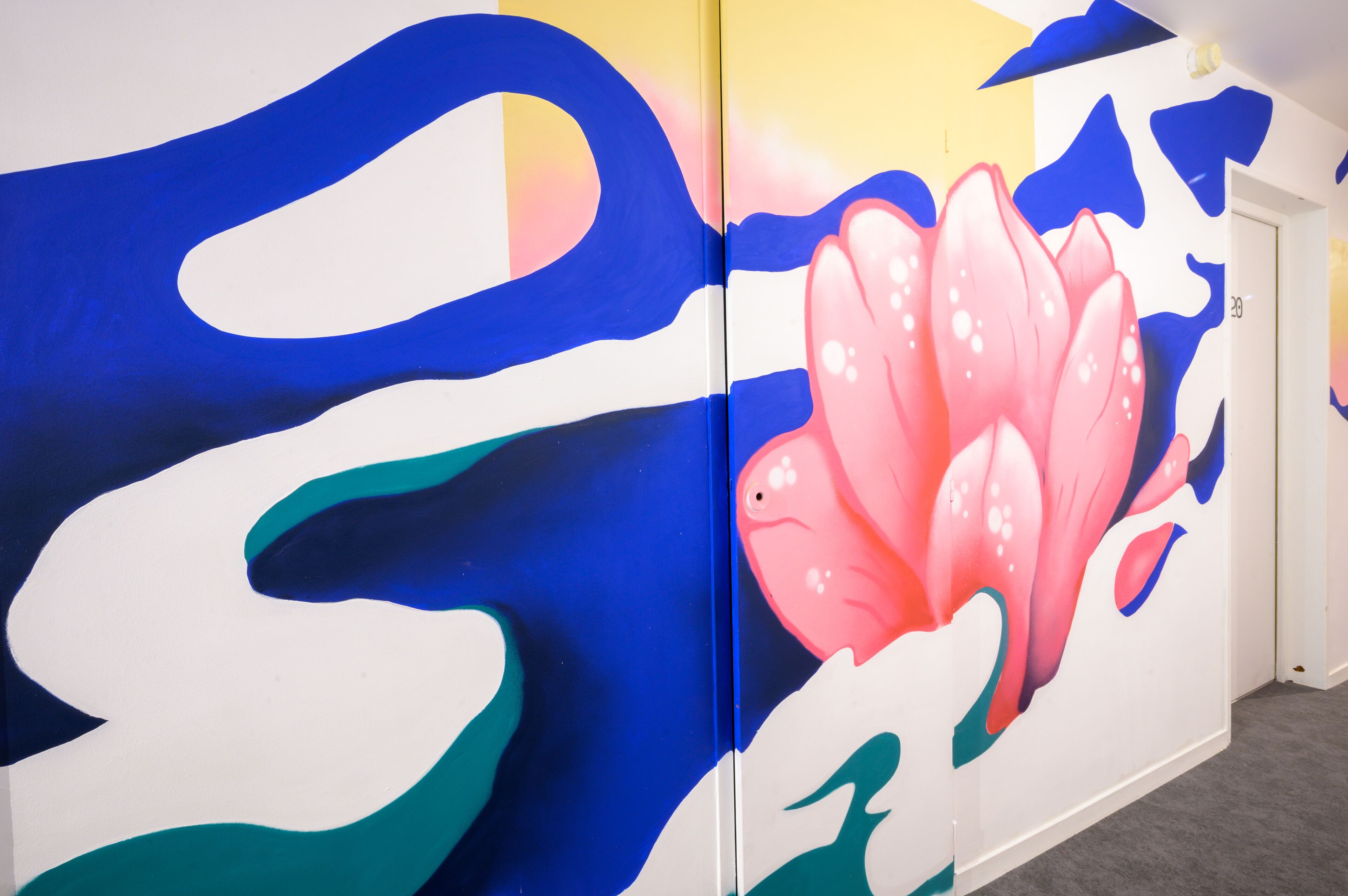 A vibrant wall mural with abstract shapes and a prominent pink lotus flower.