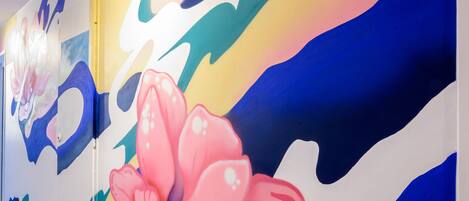 Un pasillo con llamativas obras de arte abstracto en la pared, destacando una flor rosa prominente.