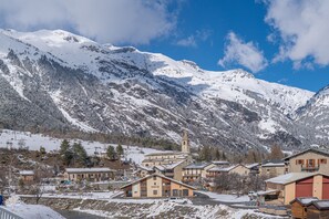 Une ville de montagne enneigée, avec une église imposante, plusieurs bâtiments et une rivière.