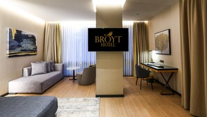 A hotel room with a sofa, a desk, a chair, a TV, and a bed. - Broyt Hotel (Istanbul)