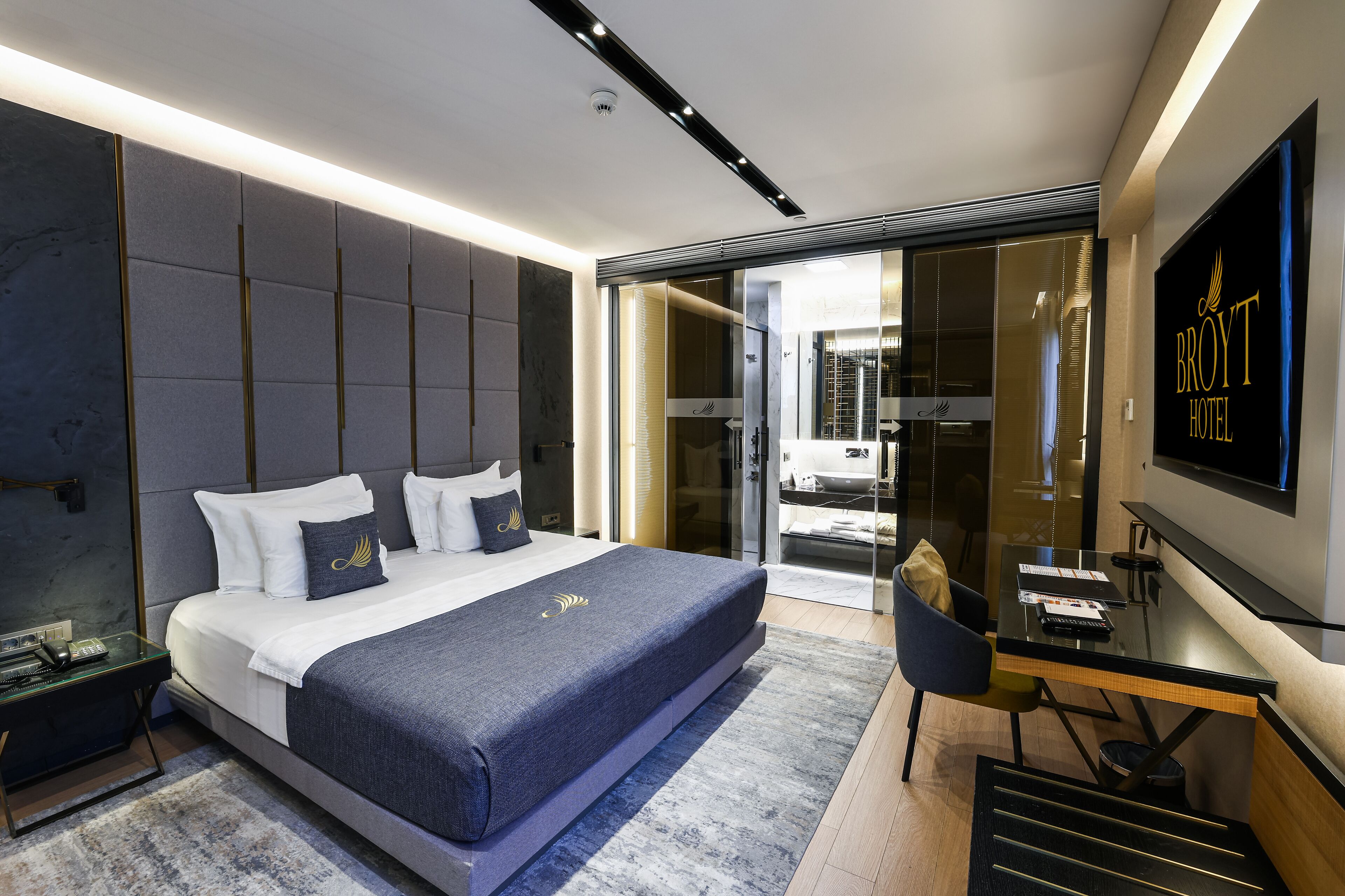 A modern hotel room with a large bed, a desk, and a TV.