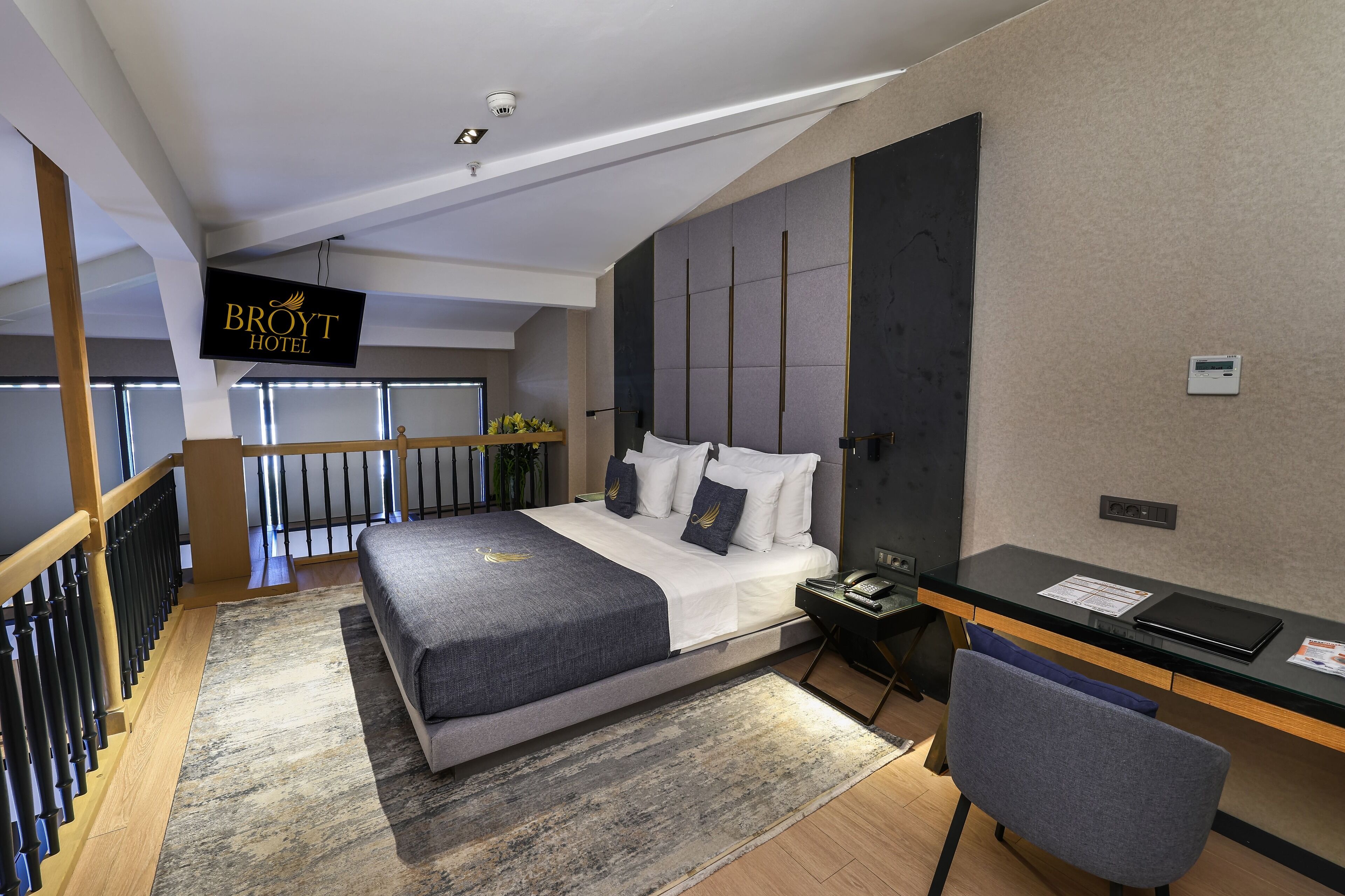 A modern hotel room with a large bed, a desk, and a chair.