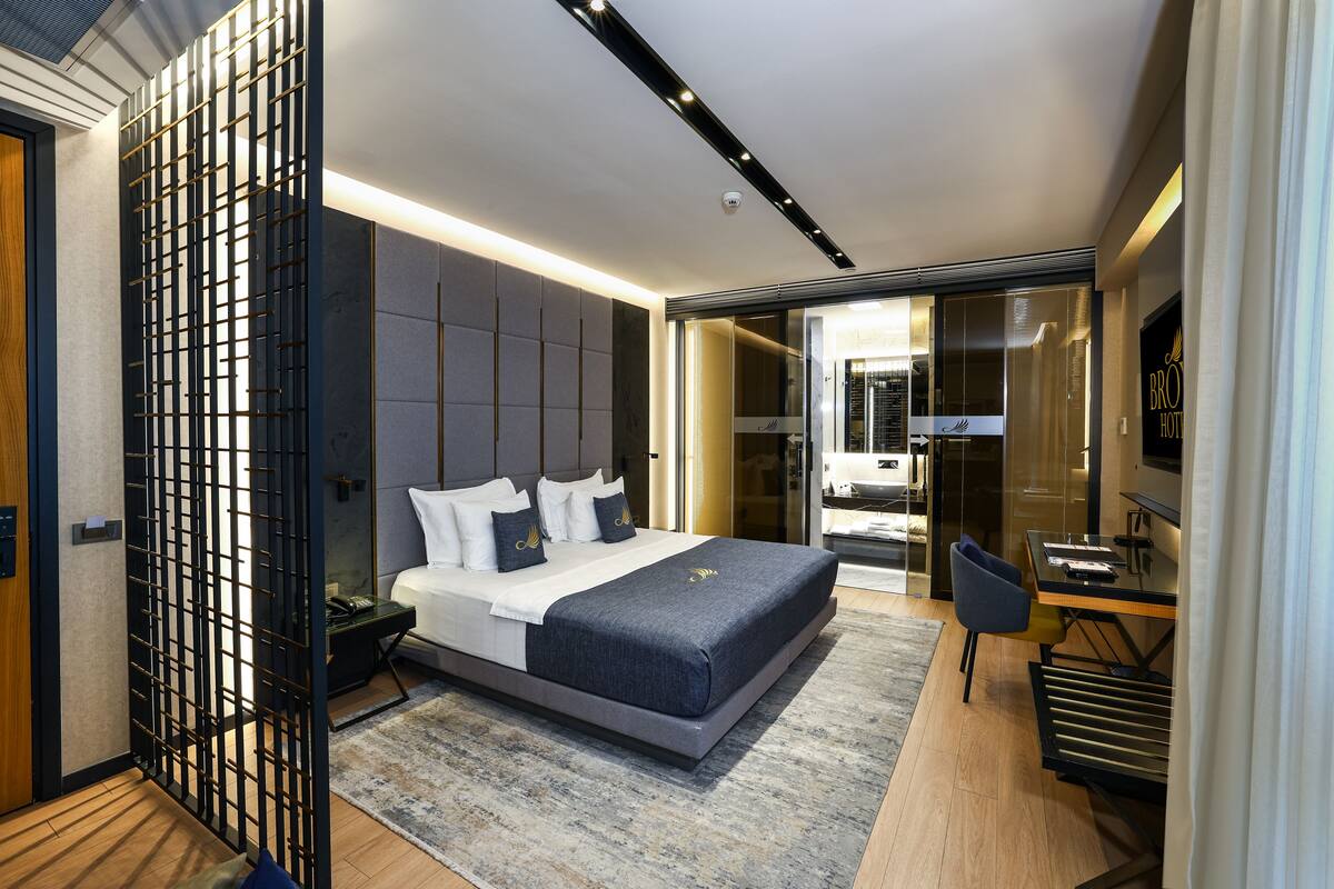 A modern hotel room with a large bed, a desk, and a seating area.