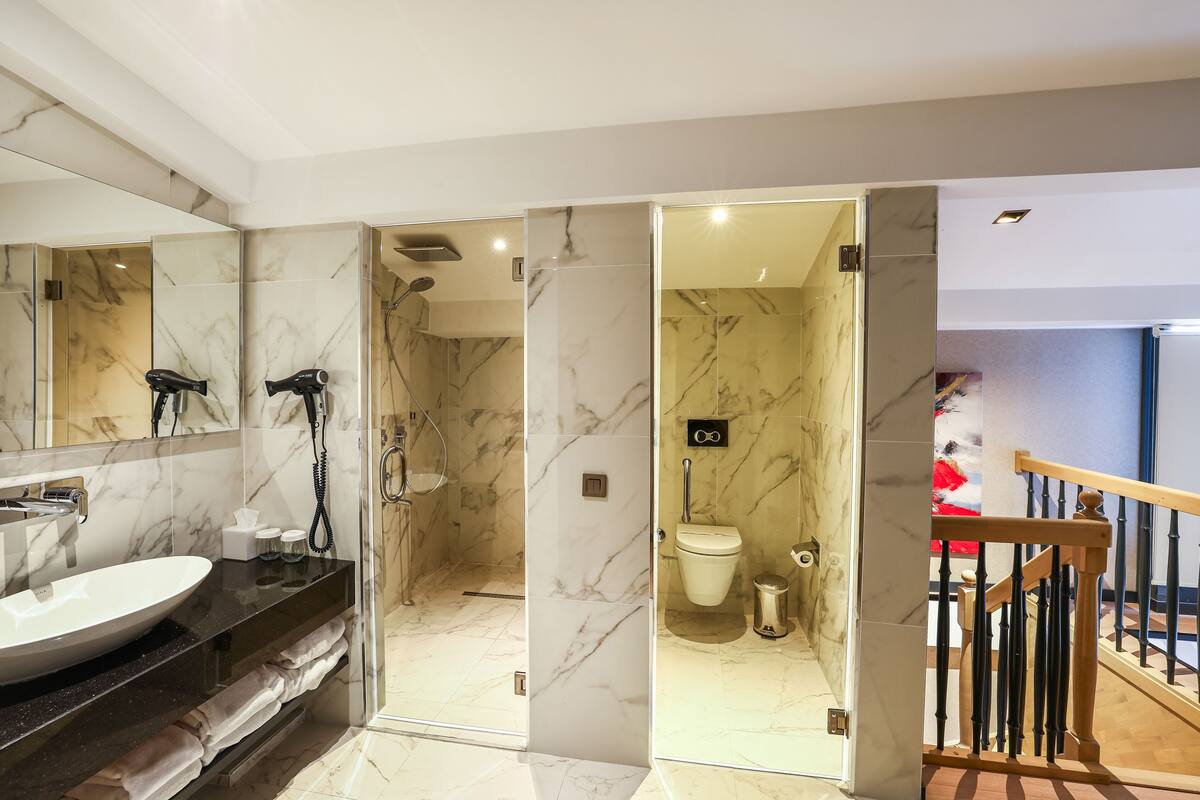 A modern bathroom with a large mirror, a sink, and a shower area.