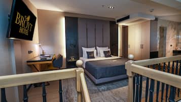 Ein modernes Hotelzimmer mit einem großen Bett, einem Schreibtisch und einem Fernseher, der den Namen des Hotels zeigt.