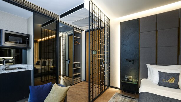A modern hotel room with a kitchenette, a walk-in closet, and a bed with a decorative pillow. - Broyt Hotel (Istanbul)