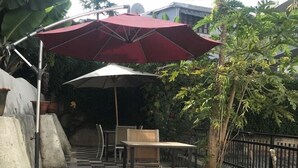 Un patio al aire libre con piso a cuadros, una mesa, sillas y un paraguas grande.