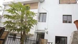 Un edificio blanco con varias ventanas y un árbol en primer plano.