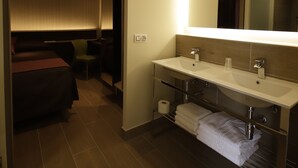 Ein modernes Hotelbad mit einem großen Spiegel, zwei Waschbecken und einer Duschkabine.