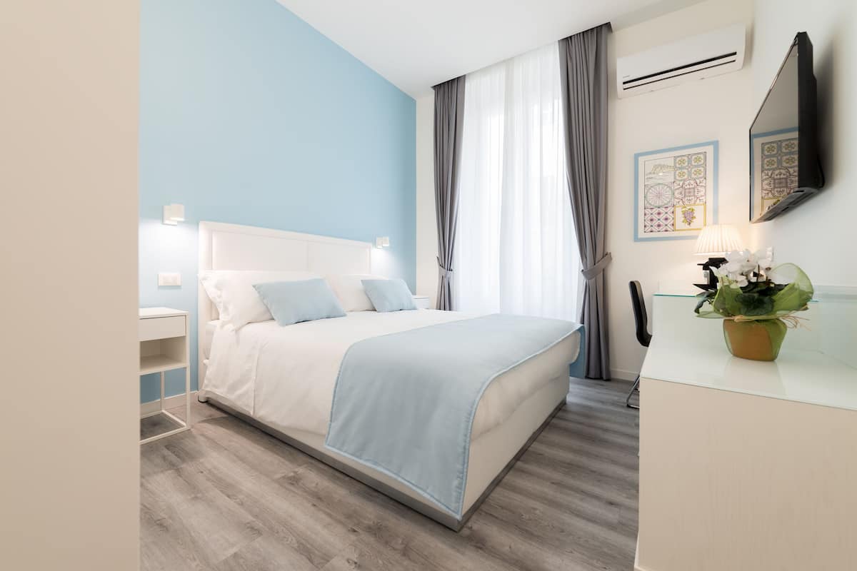 Une chambre moderne avec un lit, des tables de chevet, un bureau et une plante en pot.