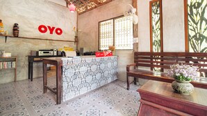 Una habitación con un mostrador de recepción, un banco de madera, un piso estampado y una pared con la palabra "OYO".