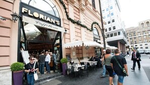 An outdoor cafe with tables and chairs, a storefront with 'FLORIAN'S Caffetteria' signage, and pedestrians walking by. - Florian Rooms  (Rome)