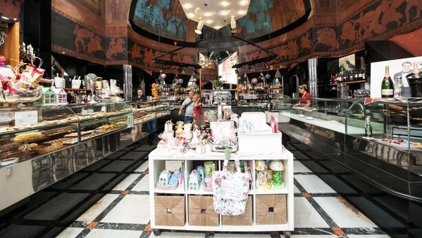 A spacious lobby with a central display of gifts and a bar area with various bottles and glasses. - Florian Rooms  (Rome)