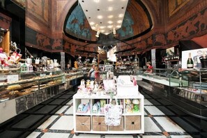 A spacious lobby with a central display of gifts and a bar area with various bottles and glasses. - Florian Rooms  (Rome)