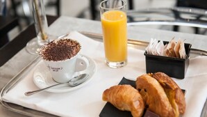 A breakfast tray with a cup of coffee, a glass of orange juice, croissants, and chocolate pieces. - Florian Rooms  (Rome)
