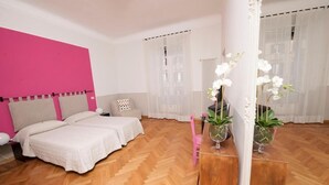 A bedroom with two beds, a mirror, and a dresser with potted plants. - Florian Rooms  (Rome)