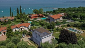 An aerial view of a residential area with houses, a swimming pool, and a view of the sea. - Casa Linda (Lazise)