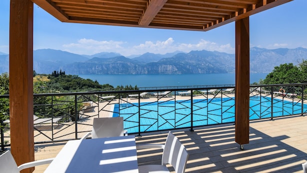 A wooden pergola overlooking a pool with a mountain view. - Garden Residence Malcesine Lake View (Malcesine)