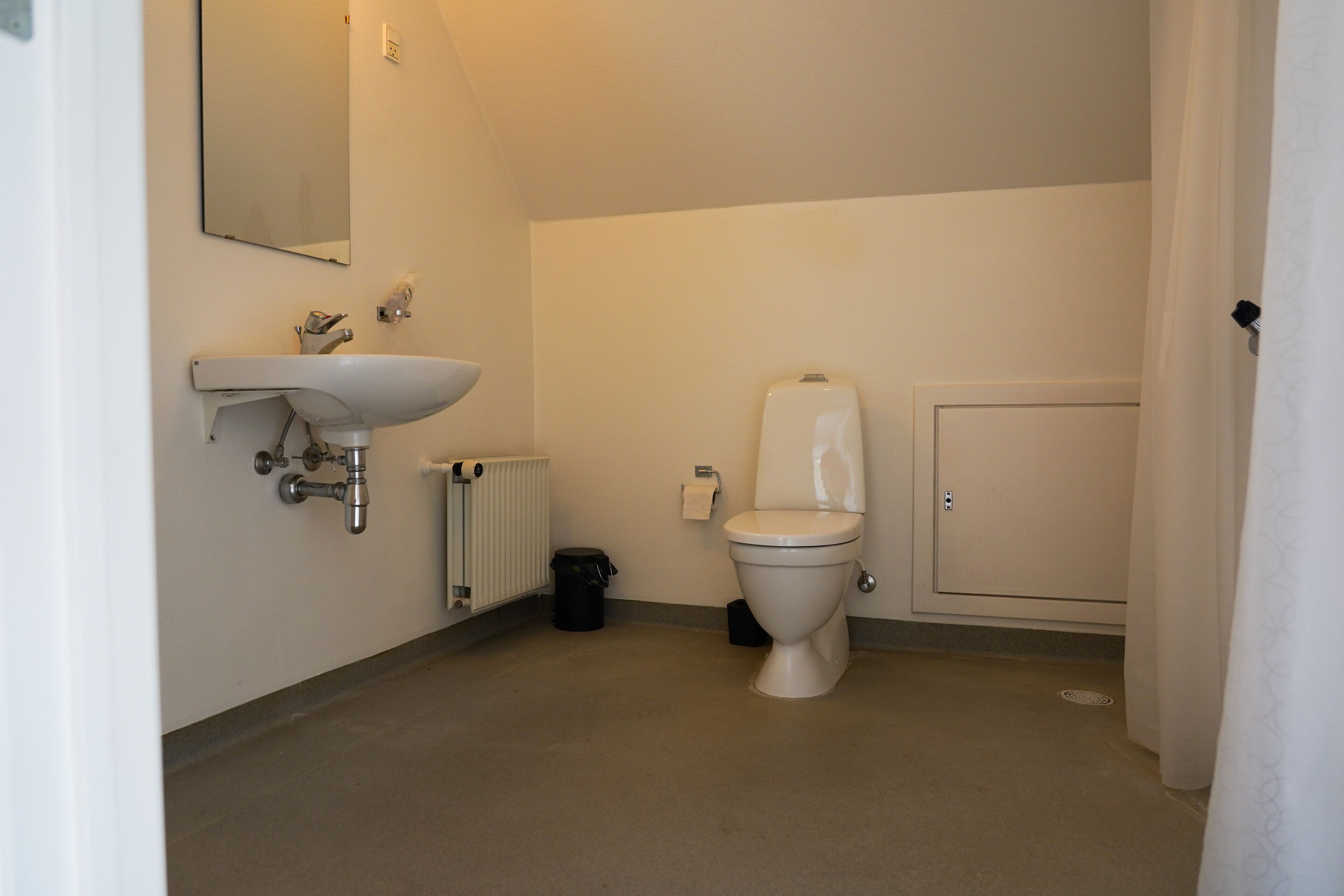 A bathroom with a toilet, sink, and a mirror on the wall.