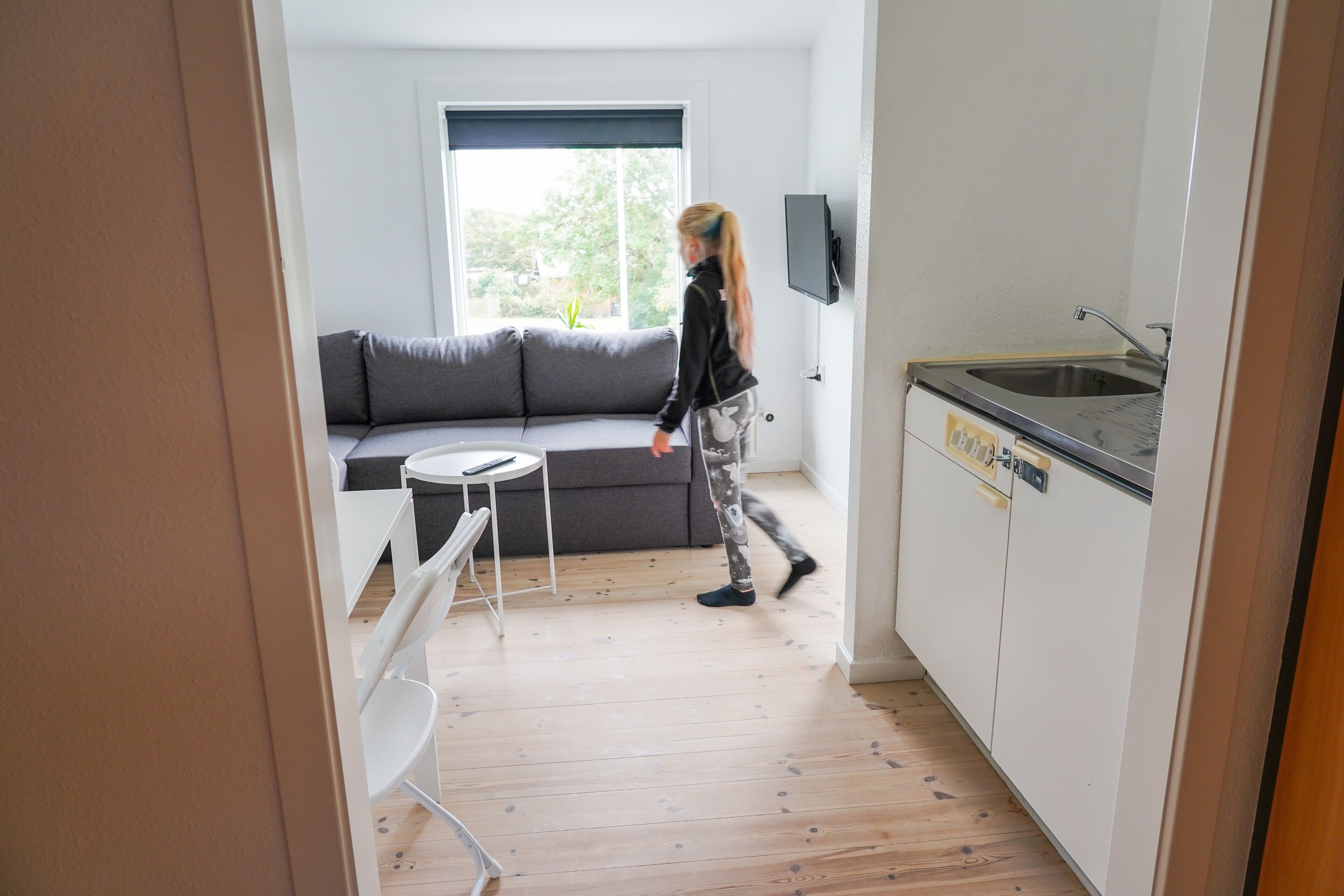 A compact living space with a sofa, a small dining table, and a kitchen area with a sink and cabinets.