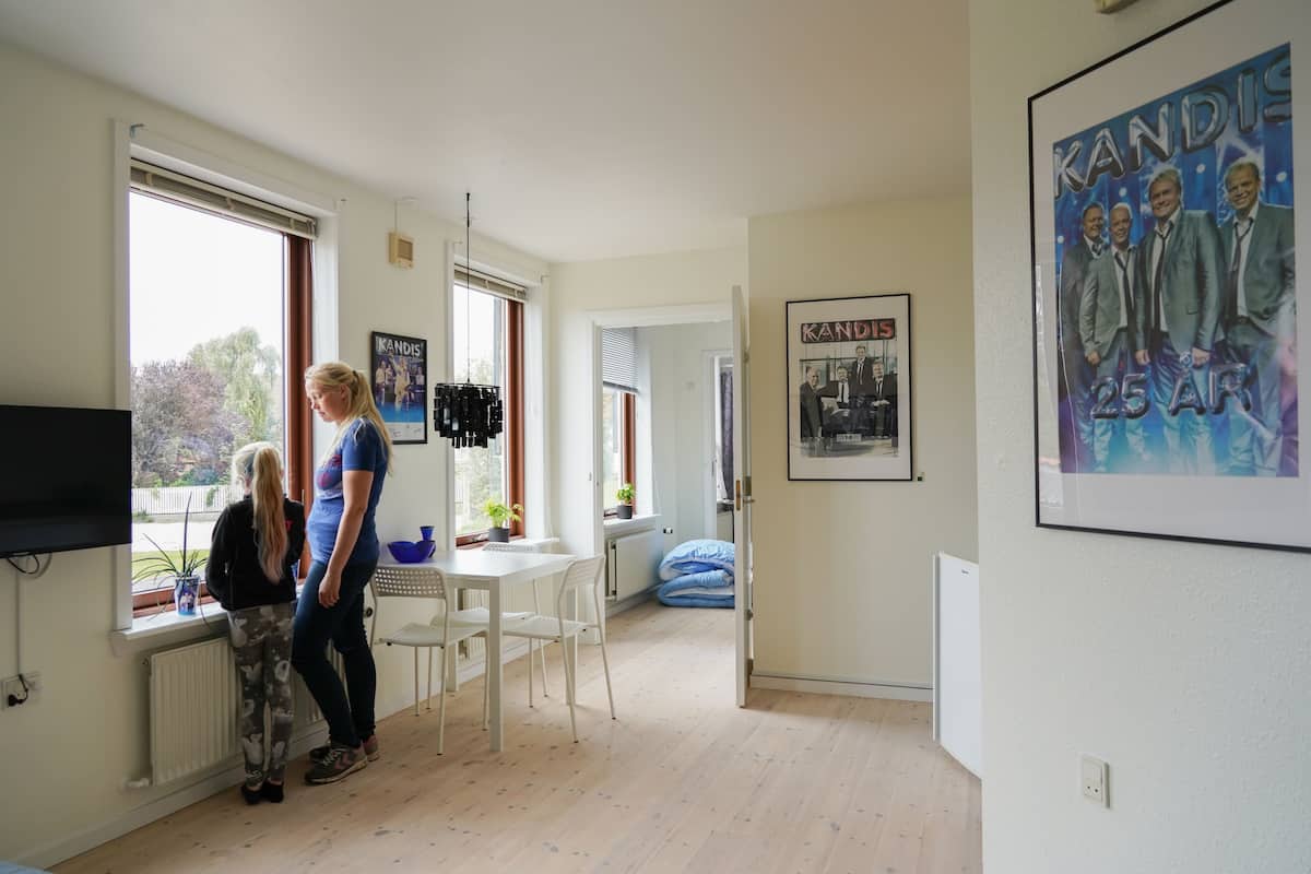 A modern kitchen with a dining area, large windows, and a poster on the wall.