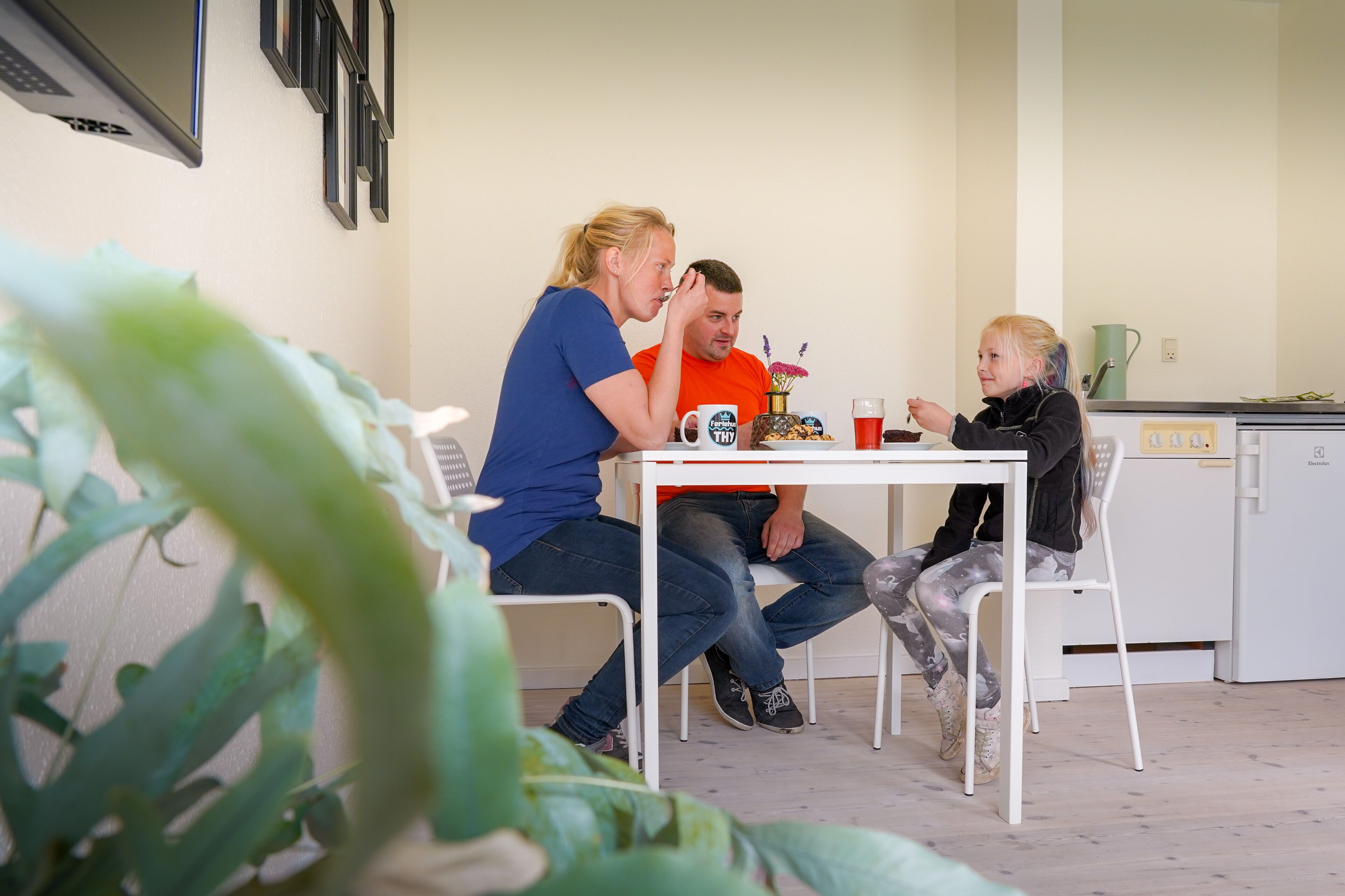 Un espace repas avec une table blanche, des chaises et une personne assise à la table.