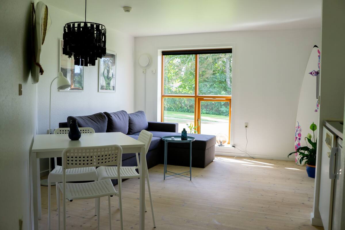 A modern living room with a white table, two white chairs, a grey sofa, and a black floor lamp.