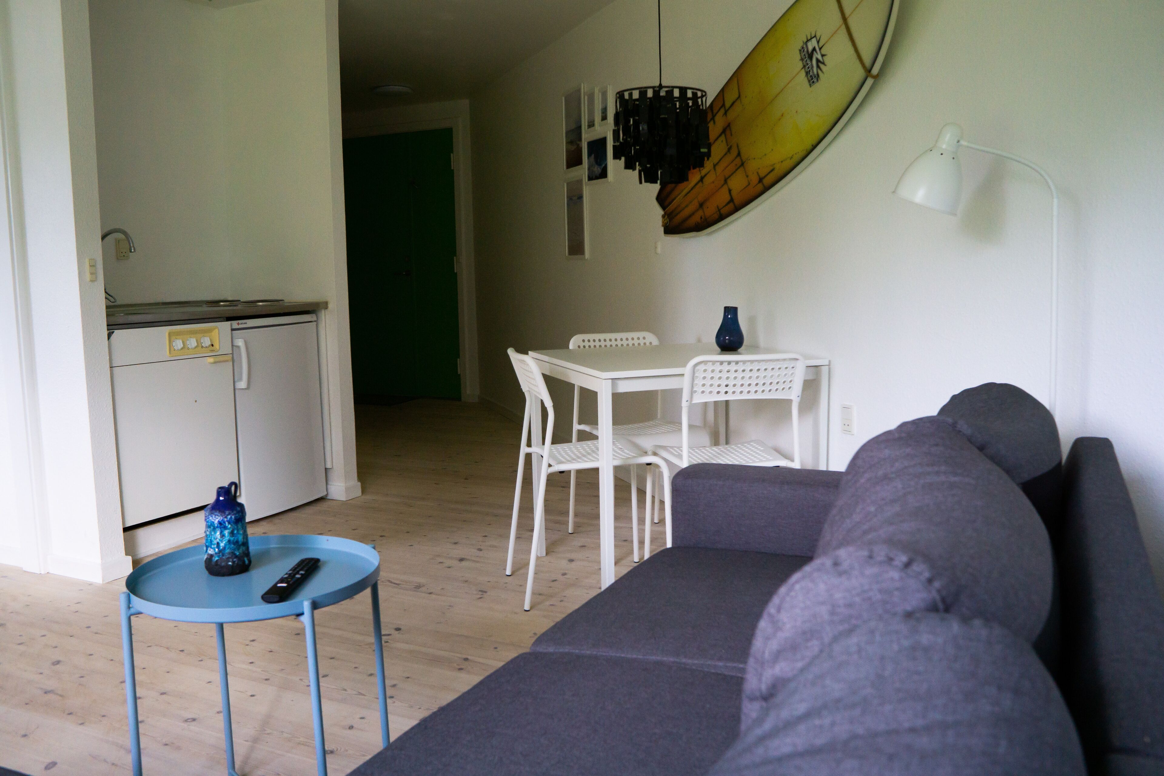 Un espace de vie compact comprenant un coin cuisine, un coin repas et un coin salon.