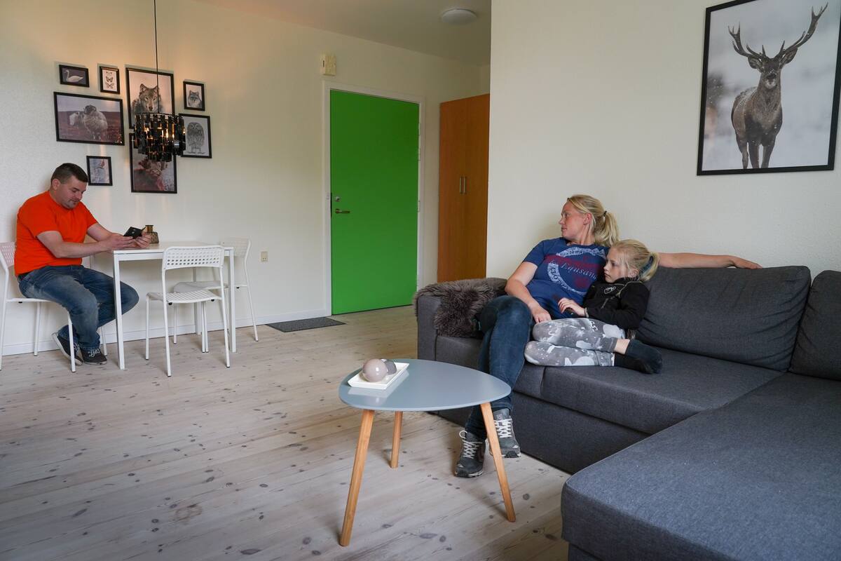 A living room with a grey sofa, a white table, and a green door.