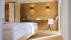 A modern hotel room with a bed, a desk, and a chair. There are two wall-mounted lights and a mirror on the wall. - Boutique Hotel Schlossberg (Thun)