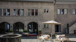 A courtyard with outdoor seating, stone walls, and arched doorways. - Boutique Hotel Schlossberg (Thun)