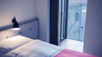 Una camera da letto con un letto, una lampada da comodino e una finestra che dà su un edificio con una scala.