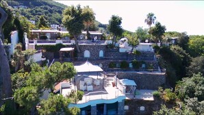 A multi-level building with outdoor seating areas, stone walls, and a mix of residential and commercial spaces. - L'Incanto Suites Ischia (Casamicciola Terme)