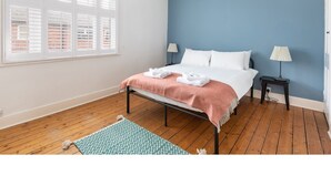 A bedroom with a bed, two bedside tables, a window with blinds, a hanging light fixture, and a patterned rug. - Charming & Trendy Base for 5, nr Bishopthorpe Rd (York)