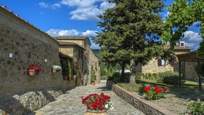 A stone building with a courtyard, potted plants, and a clear blue sky. - Il Villino Della Rocca (Castellina in Chianti)