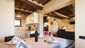 A dining area with a table set for two, a bottle of wine, and a red wine glass. - Il Villino Della Rocca (Castellina in Chianti)
