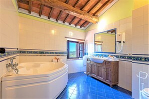 A bathroom with a large bathtub, wooden cabinets, a sink, and a mirror.