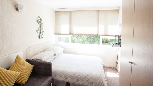 A bedroom with a bed, a bedside table, a wardrobe, and a window with blinds. - 2BD Apartment, 500m From Windsor Castle, Parking (Windsor)