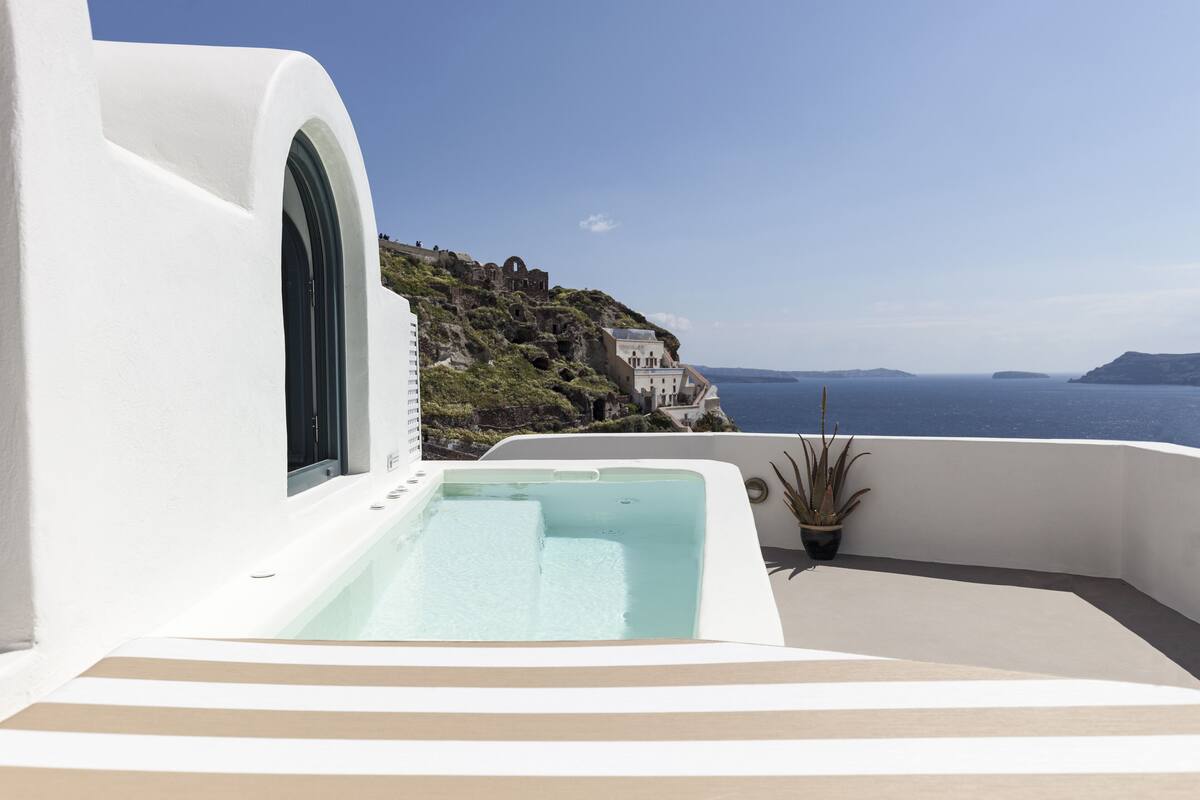 A modern white building with a large window and a pool area.