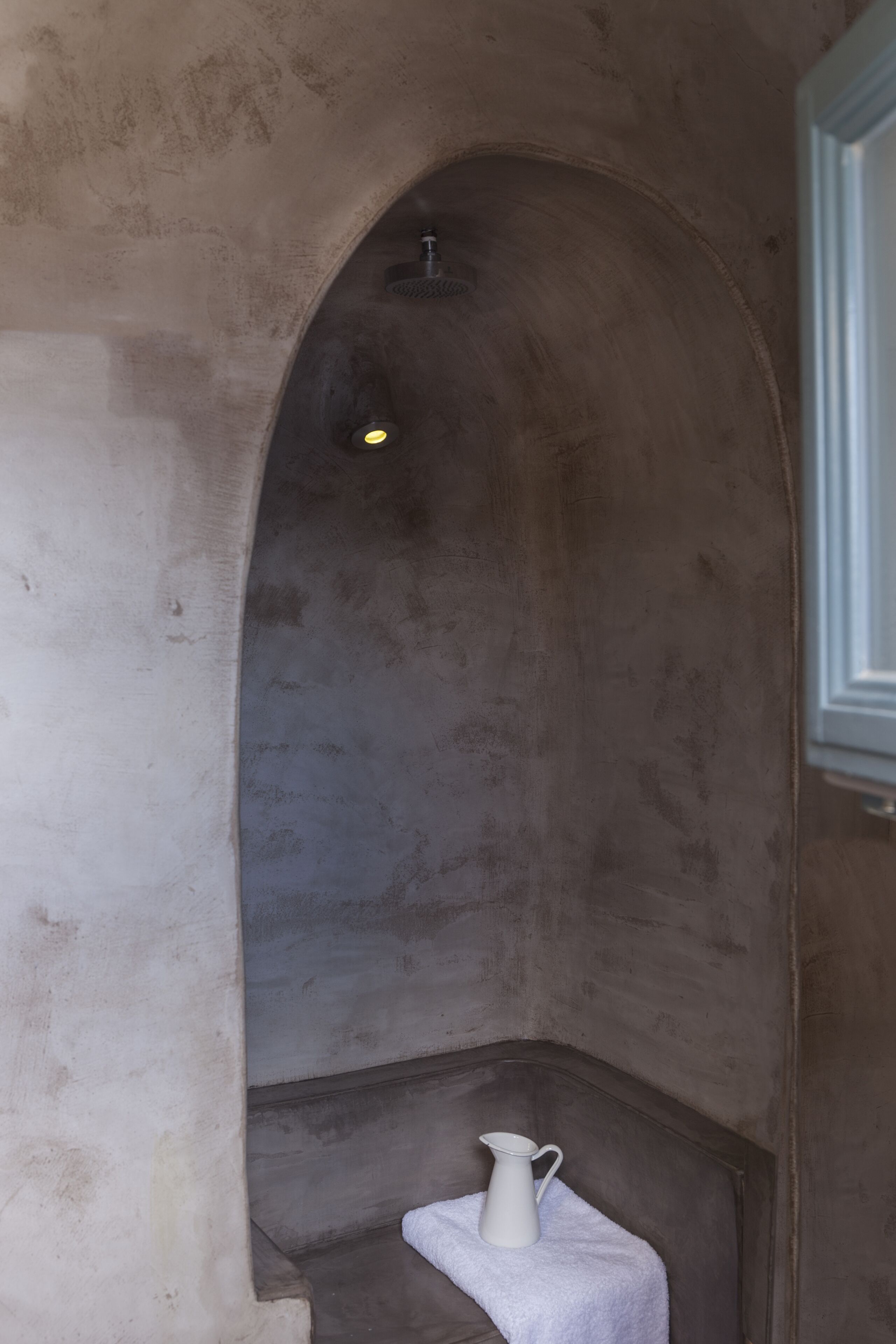 A narrow, arched alcove with a white pitcher on a small table.