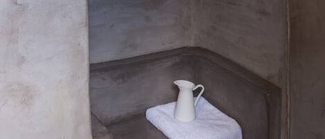 A narrow, arched alcove with a white pitcher on a small table.