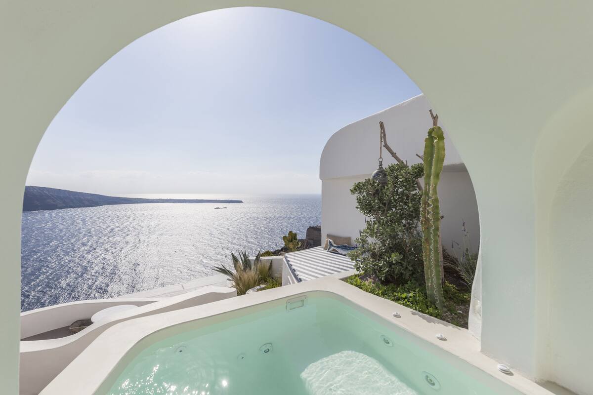 A hot tub with a view of the sea and a cactus plant.